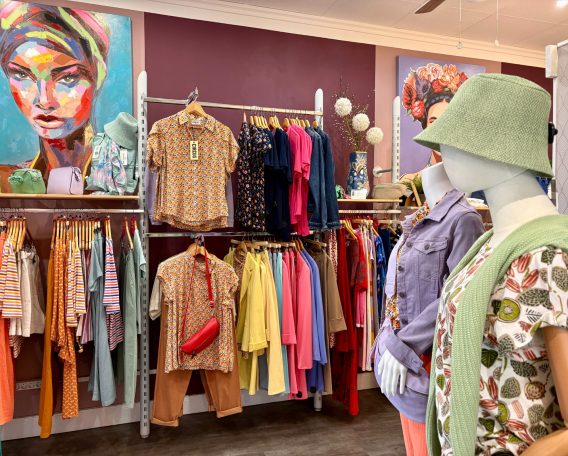 Modegeschäft mit farbenfrohen Kleidung, manuellem Zubehör und bunten Wandbildern.